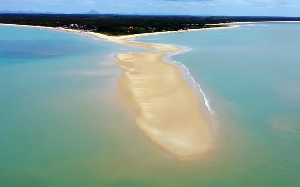 Vista aérea da ponta do corumbau, uma faixa de areia que avança no mar da Bahia, com águas claras e vegetação na costa.