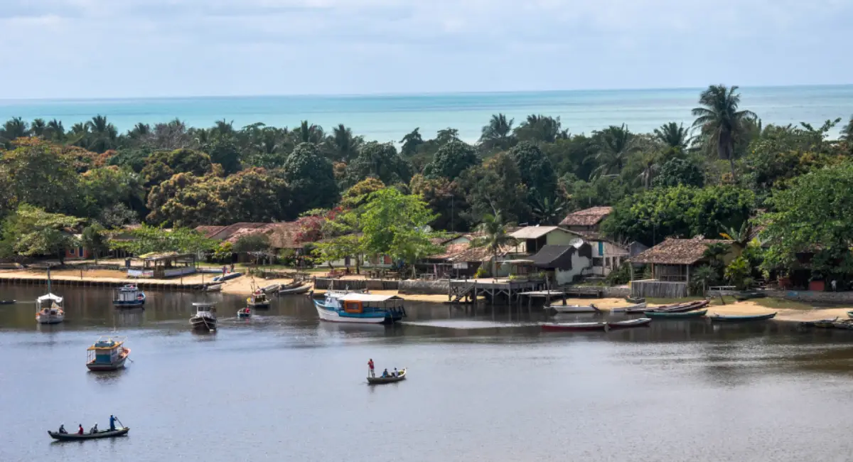 Travessia do Rio Caraíva com o vilarejo e a praia ao fundo, principal ponto do roteiro arraial caraiva trancoso.