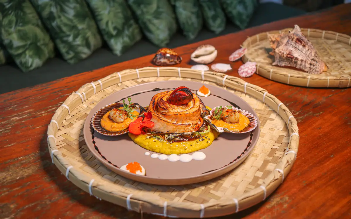 Prato gourmet com camarões grelhados e arroz cremoso, servido em travessa de palha, representando a culinária do Festival Gastronômico Esquina do Mundo em Arraial d'Ajuda.