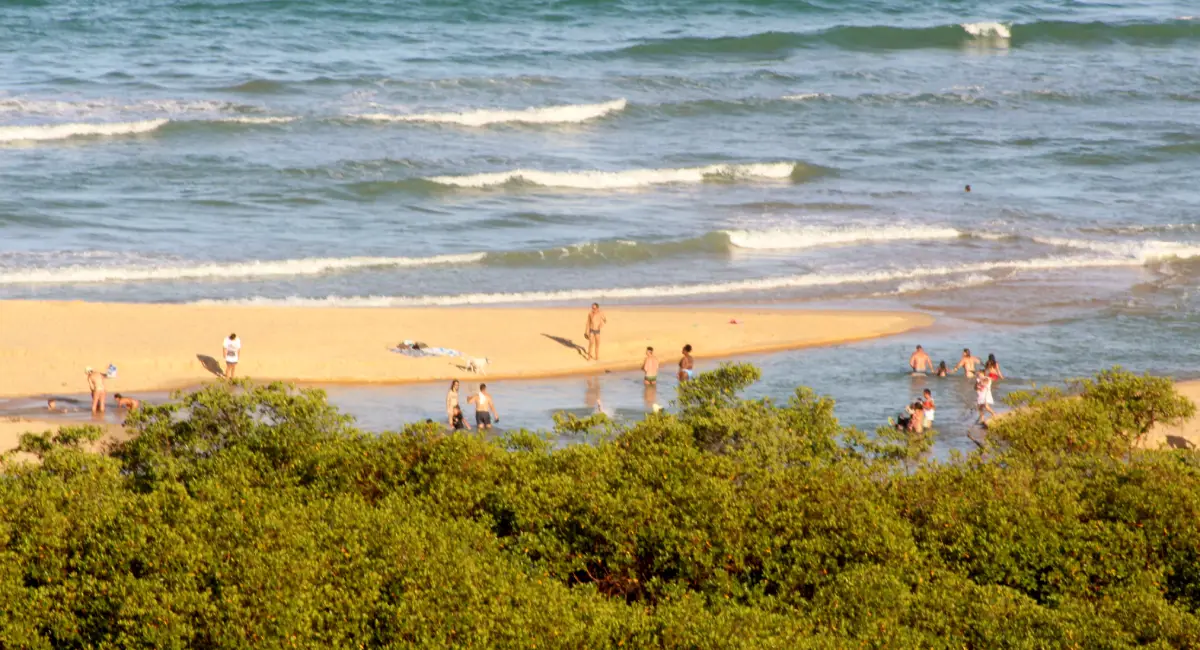 Vista aérea de banhistas em banco de areia entre o mar e a foz de um rio em Trancoso ou Arraial d'Ajuda, Bahia.